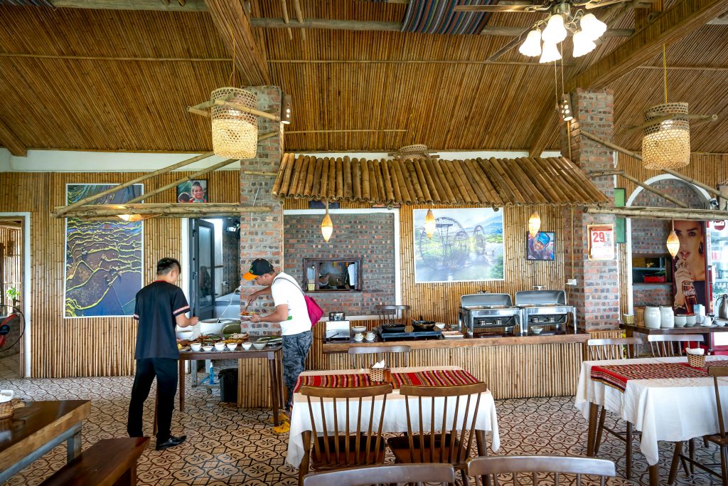 Charming bamboo café with rustic decor and people serving food.