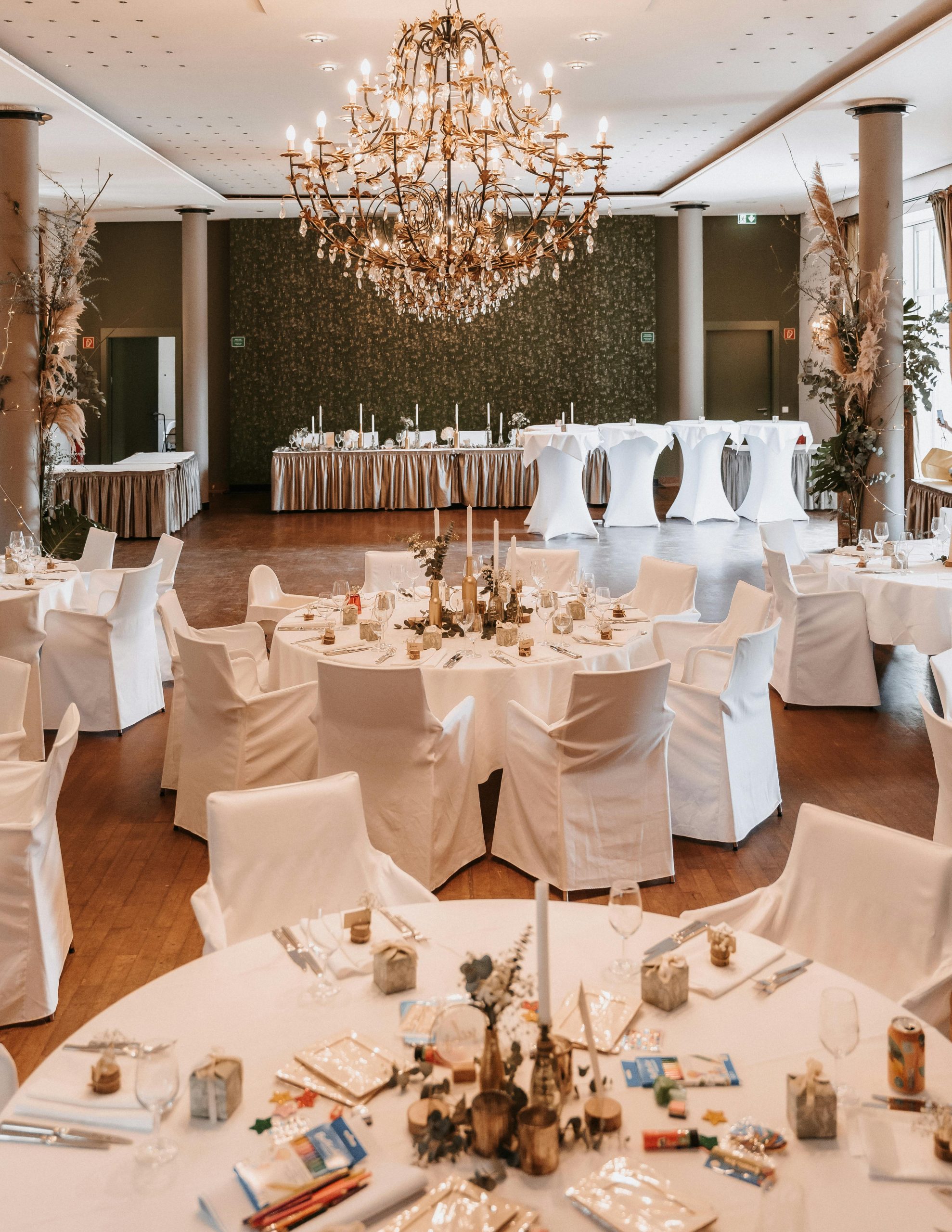 Beautifully decorated wedding reception hall with chandeliers, set tables, and elegant decor.